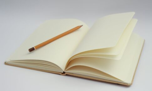 white notebook and yellow pencil